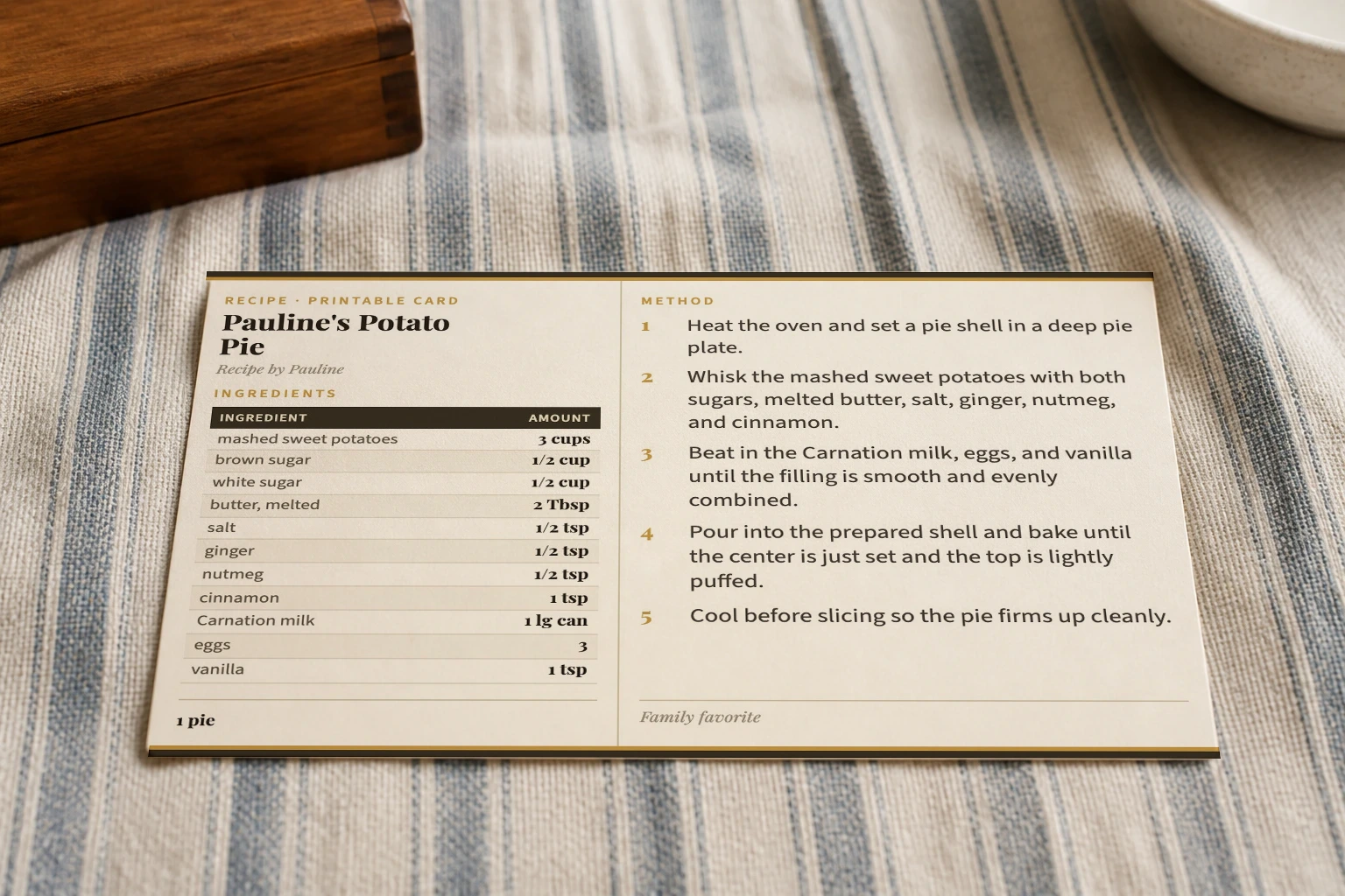 Printed Pauline's Potato Pie recipe card on blue-striped linen beside a wooden recipe box